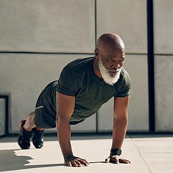 An older man performing push-ups on a concrete floor, demonstrating strength and fitness.