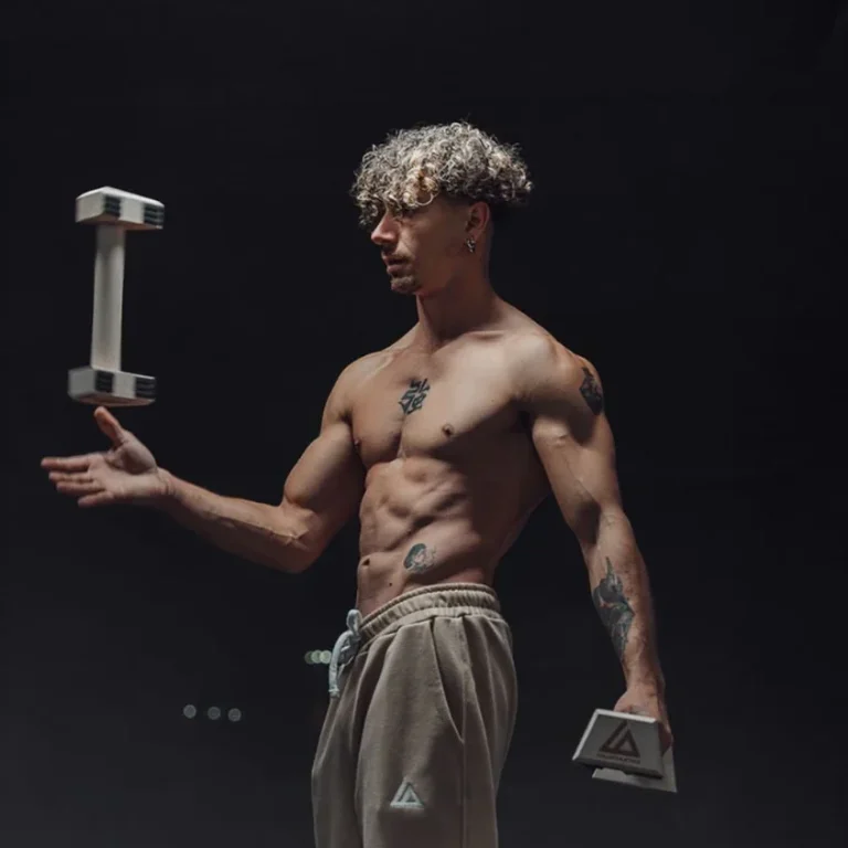 A shirtless man grips a dumbbell in low light, highlighting his dedication to weightlifting and physical fitness.  